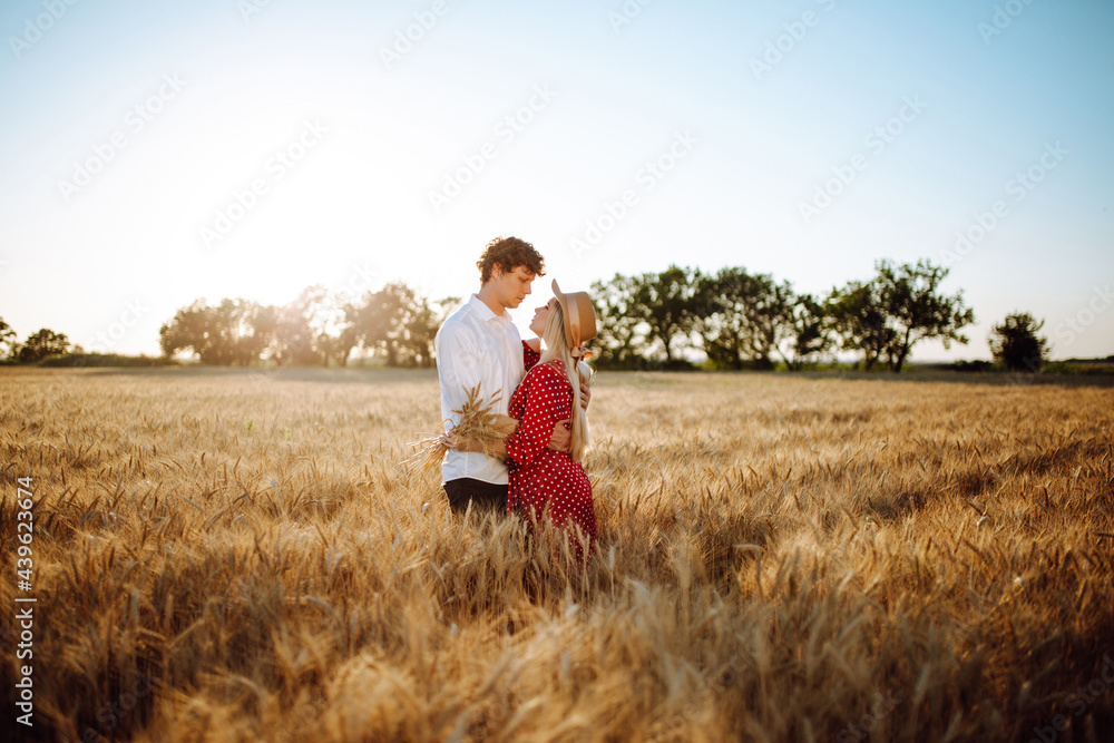 A loving couple posing in a wheat field. Portrait of a man and a woman at sunset. Summer landscape. Warm colors. The concept of youth, love and lifestyle. A loving couple posing in a wheat field. Portrait of a man and a woman at sunset. Summer landscape. Warm colors. The concept of youth, love and lifestyle.