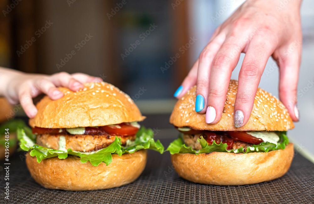Small child's hand and mother's hand on homemade homemade burgers. The concept of cooking delicious food at home with your child, close-up Small child's hand and mother's hand on homemade homemade burgers. The concept of cooking delicious food at home with your child, close-up