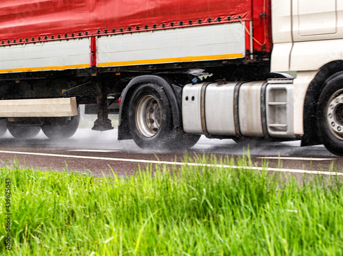 Truck tires in wet weather on wet asphalt. Wet weather road safety concept. Braking distance and aquaplaning characteristics on the road. Close-up