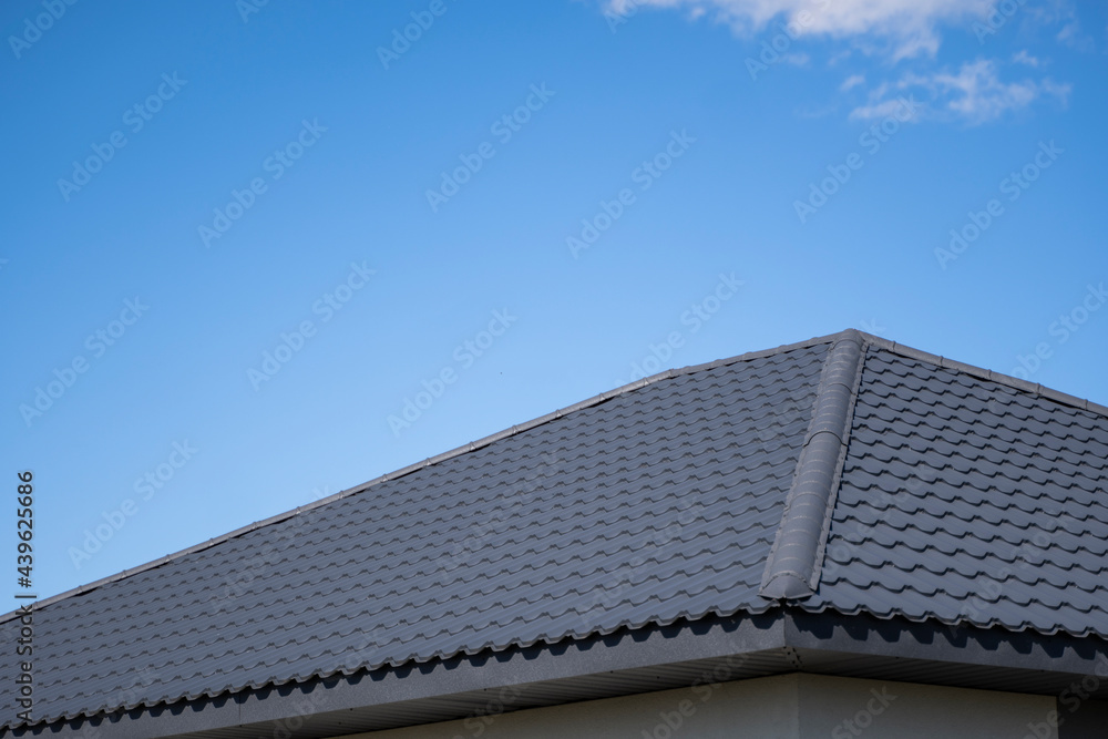 Brown corrugated metal profile roof installed on a modern house. The roof of corrugated sheet. Roofing of metal profile wavy shape. Modern roof made of metal. Metal roofing. Brown corrugated metal profile roof installed on a modern house. The roof of corrugated sheet. Roofing of metal profile wavy shape. Modern roof made of metal. Metal roofing.