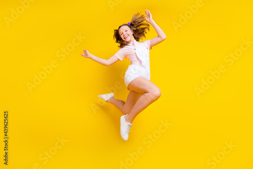 Full length body size photo schoolgirl jumping high carefree isolated bright yellow color background