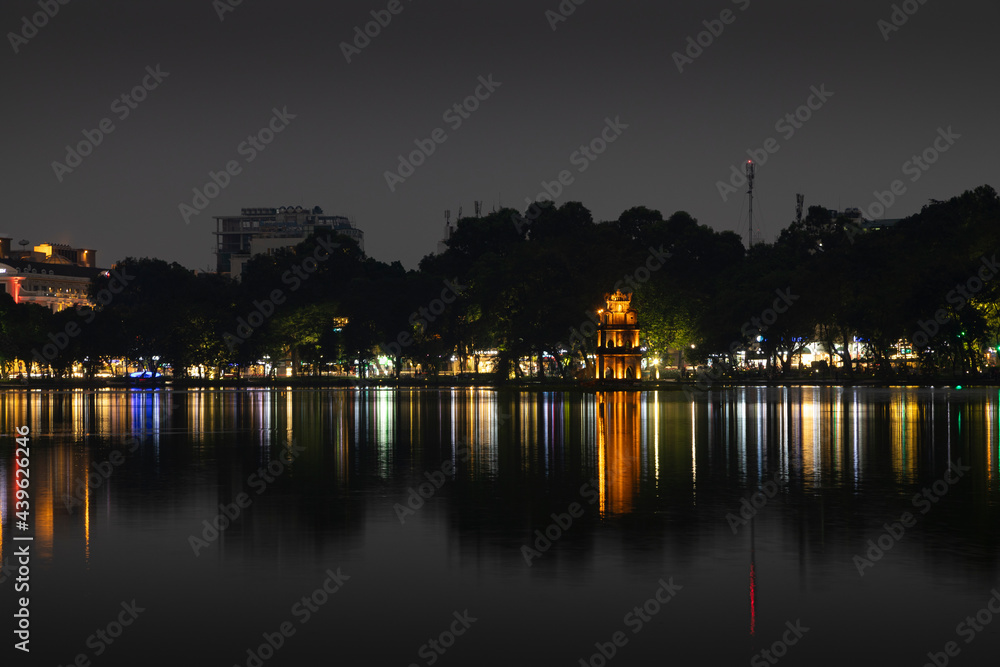Hoan Kiem Lake, meaning Lake of the Returned Sword, at night with the lights of Hanoi, in Vietnam, reflected on the smooth surface of the water