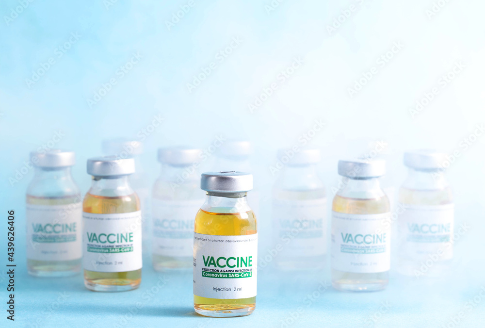 Coronavirus vaccine dose bottles on blue background covered in smoke. Kotsnept developing and testing a new vaccine in the laboratory Coronavirus vaccine dose bottles on blue background covered in smoke. Kotsnept developing and testing a new vaccine in the laboratory