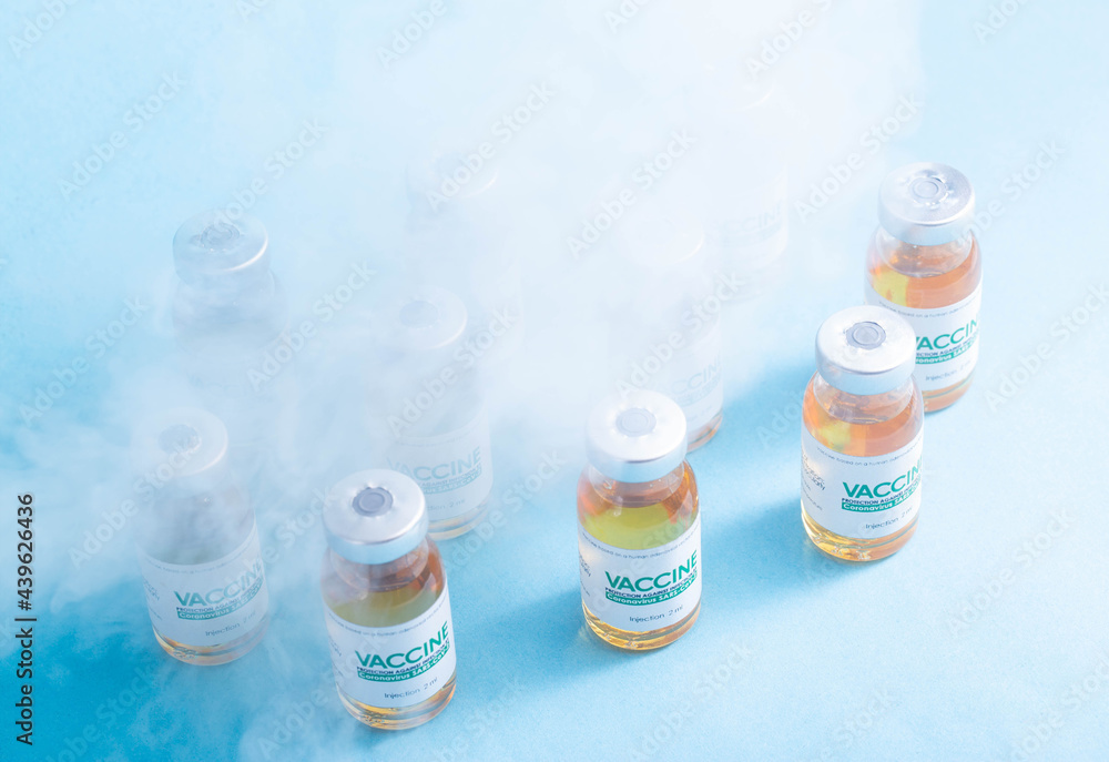 Coronavirus vaccine dose bottles on blue background covered in smoke. Kotsnept developing and testing a new vaccine in the laboratory