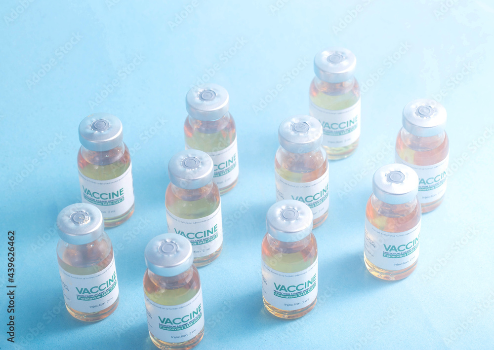 Coronavirus vaccine dose bottles on blue background covered in smoke. Kotsnept developing and testing a new vaccine in the laboratory Coronavirus vaccine dose bottles on blue background covered in smoke. Kotsnept developing and testing a new vaccine in the laboratory