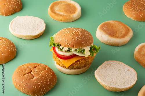 Crispy chicken burger with cheese on green background