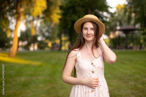 beautiful girl in dress and hat against the backdrop of a sunlit garden