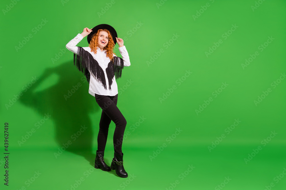 Full length body size view of attractive thin cheerful girl touching hat posing having fun isolated over bright green color background Full length body size view of attractive thin cheerful girl touching hat posing having fun isolated over bright green color background