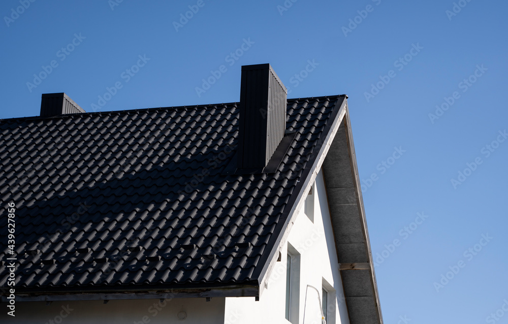 Grey corrugated metal profile roof installed on a modern house. The roof of corrugated sheet. Roofing of metal profile wavy shape. Modern roof made of metal. Metal roofing. Grey corrugated metal profile roof installed on a modern house. The roof of corrugated sheet. Roofing of metal profile wavy shape. Modern roof made of metal. Metal roofing.