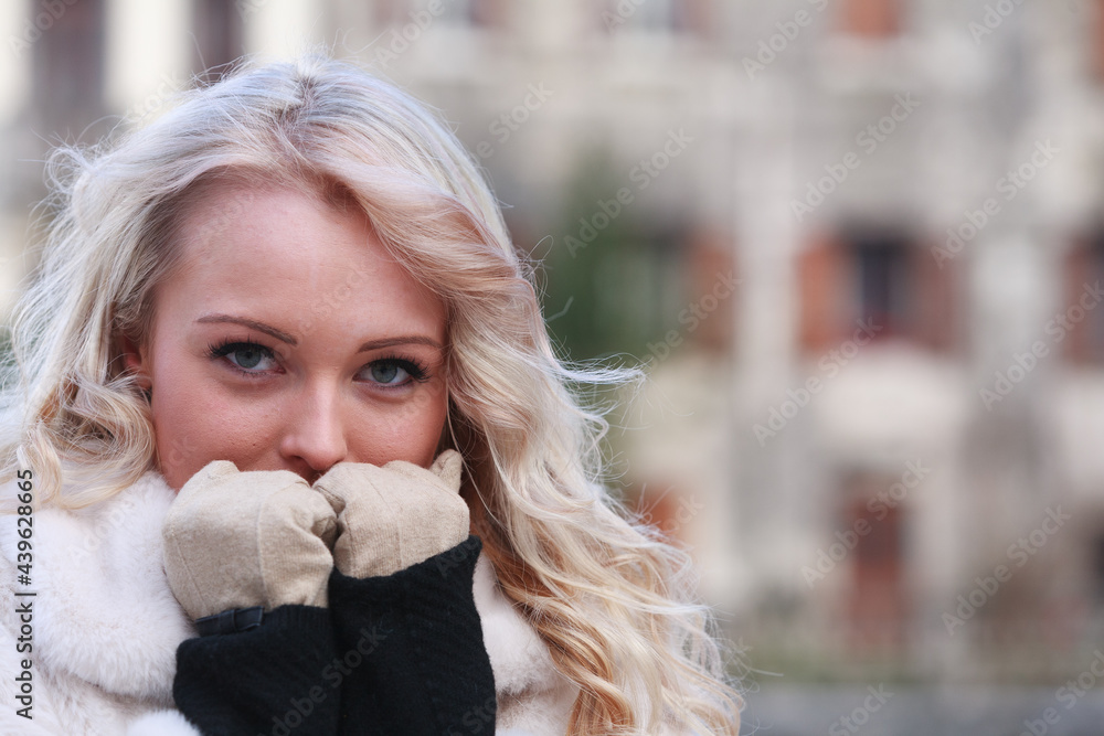 Thoughtful young woman holding her gloved hands to her face Thoughtful young woman holding her gloved hands to her face