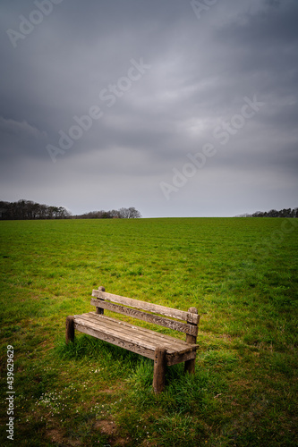 Dark and rainy clouds over bench in the countryside