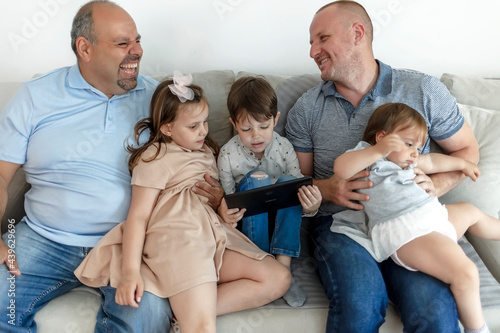 Cropped shot of an affectionate family of five using digital tablet on the sofa at home. Family reading on digital tablet together at home. Parents and kids using digital tablet at home. Copy space. © Jelena Stanojkovic