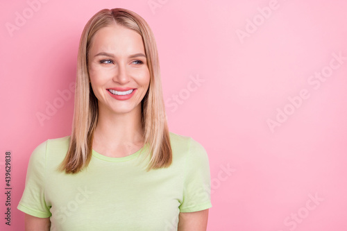 Photo of dreamy curious positive lady look side empty space wear green t-shirt isolated on pink background