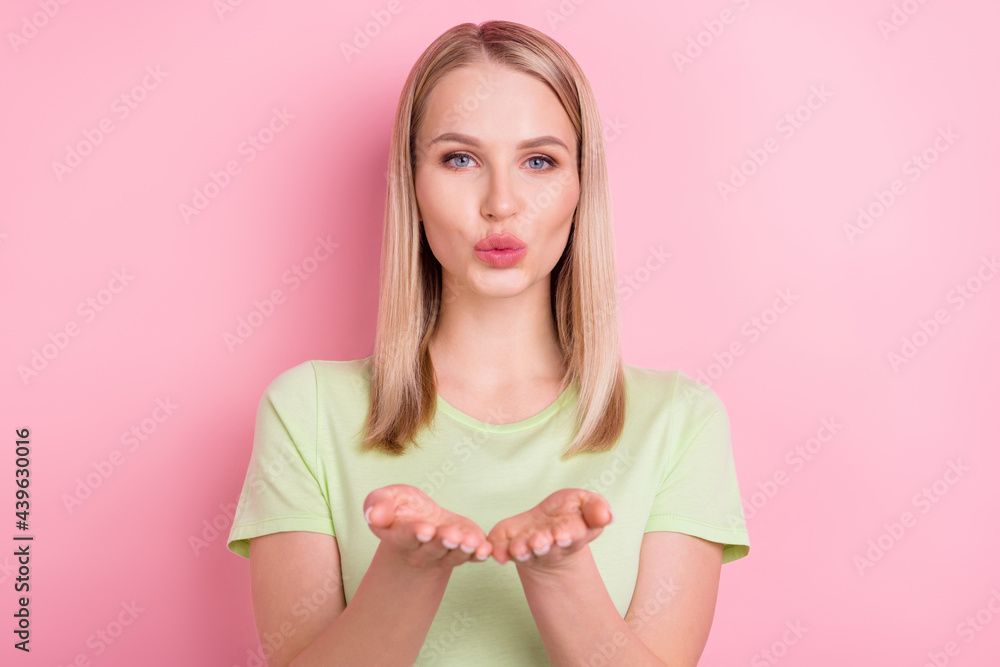 Photo of adorable affectionate lady hold palms send air kiss wear green t-shirt isolated on pink background Photo of adorable affectionate lady hold palms send air kiss wear green t-shirt isolated on pink background