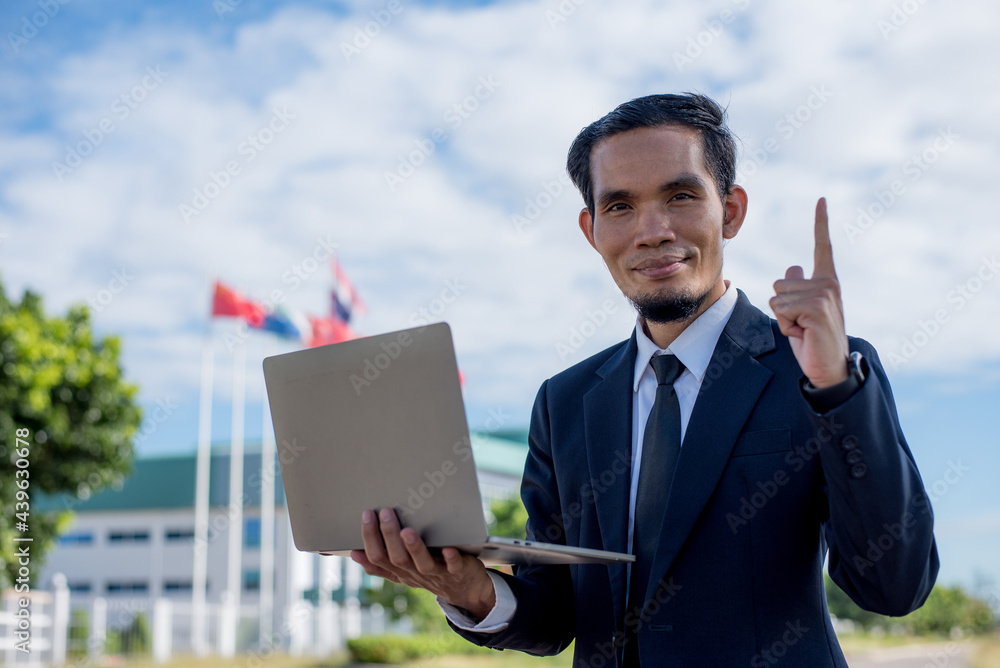 Young businessman thumbs up and laptop in another hand, business, and technology concept Young businessman thumbs up and laptop in another hand, business, and technology concept