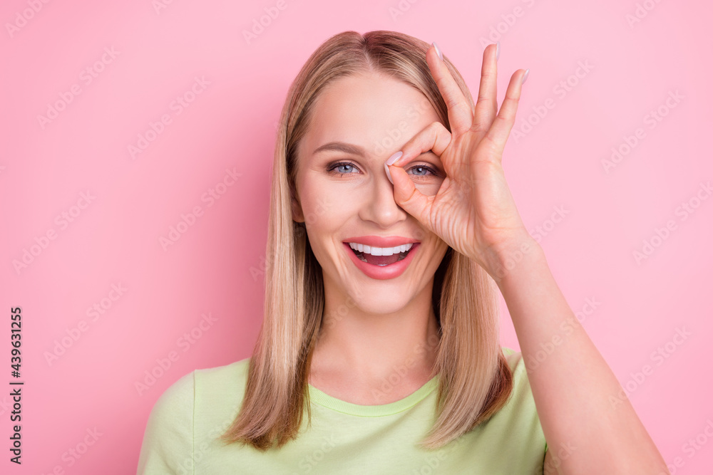 Photo of cheerful positive foolish lady make okey sign cover eye wear green t-shirt isolated on pink background Photo of cheerful positive foolish lady make okey sign cover eye wear green t-shirt isolated on pink background