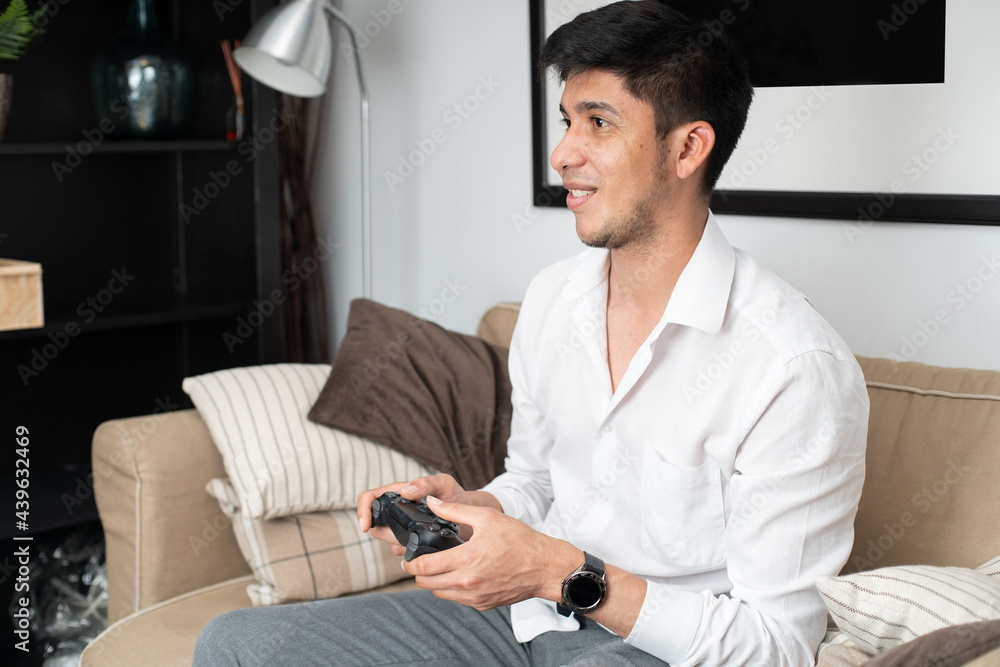 Latin man playing console on sofa Latin man playing console on sofa
