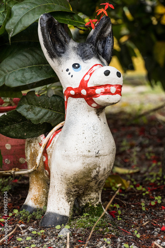 Garden with sculpture of a snow white horse. White ceramic doll. Selective focus.  photo