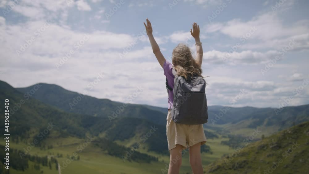 Child traveler with backpack stands in mountains hands up, enjoys view of cliff and admires nature. Little girl tourist in beautiful mountainous area Child traveler with backpack stands in mountains hands up, enjoys view of cliff and admires nature. Little girl tourist in beautiful mountainous area