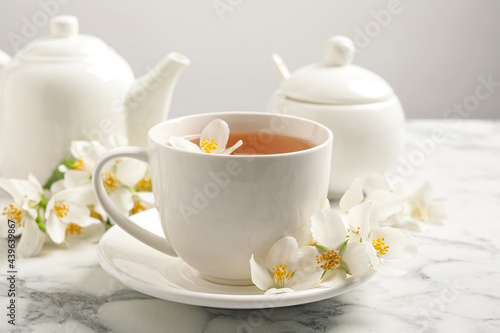 Aromatic jasmine tea and fresh flowers on white marble table