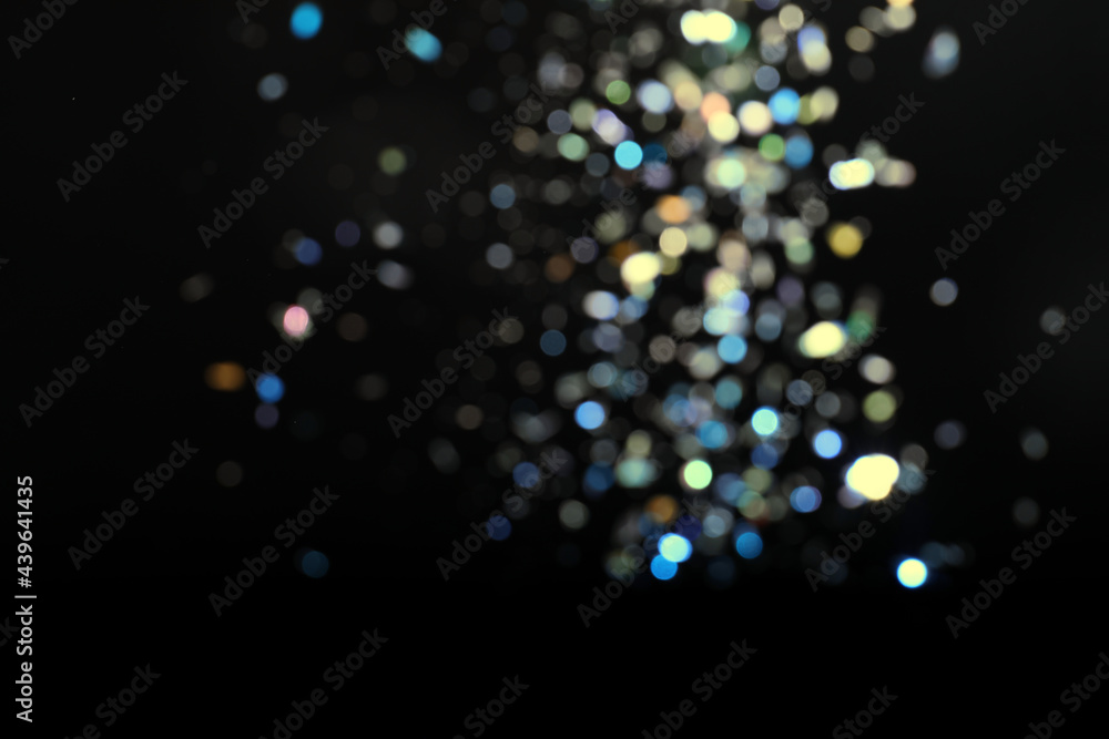 Blurred view of colorful festive lights on black background. Bokeh effect