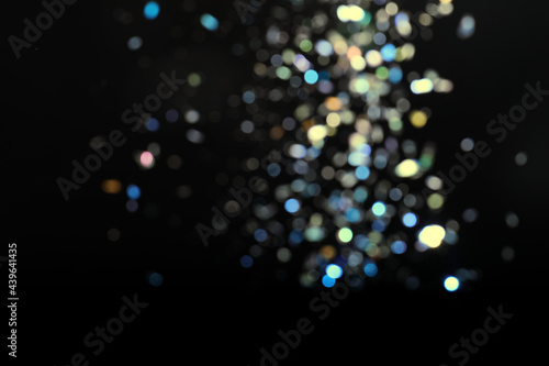 Blurred view of colorful festive lights on black background. Bokeh effect