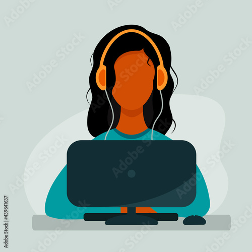 Girl with headphones listening to music and working or studying at the computer
