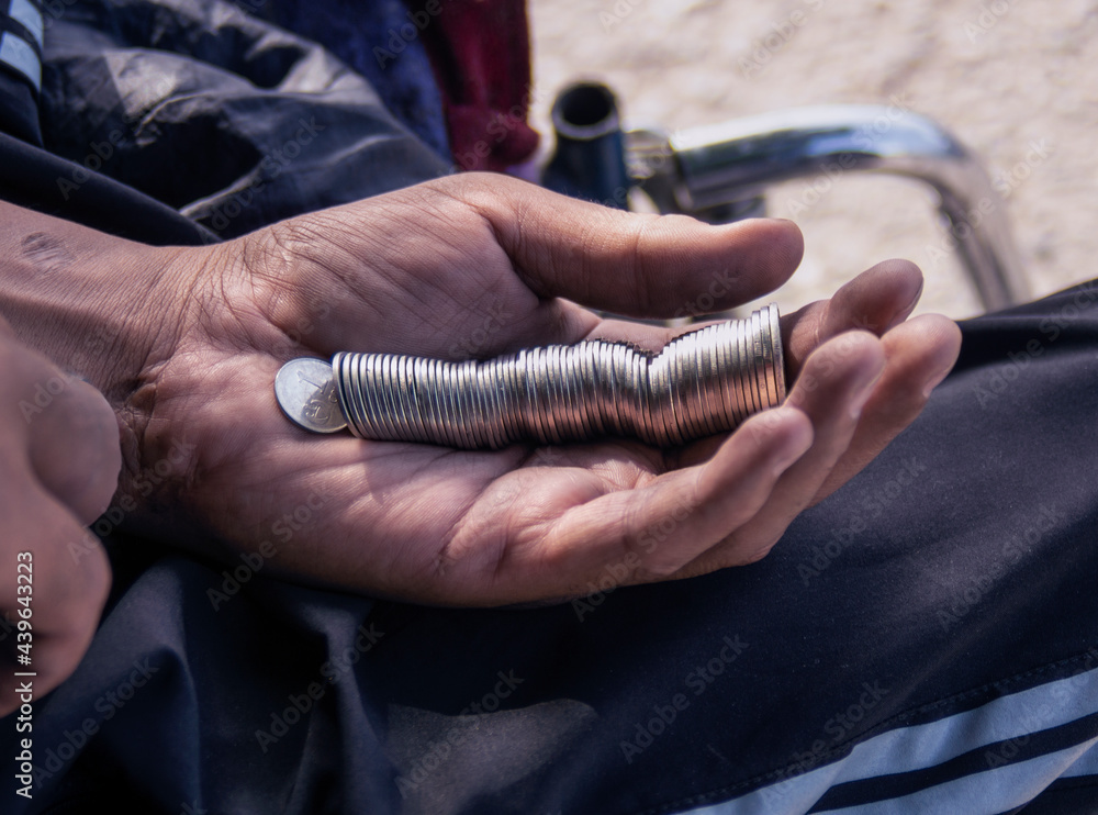 Close-up of a dirty hand with coins, begging for money or making a donation.