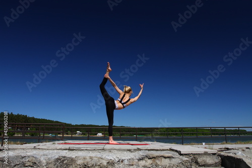 Blonde girl in sportswear relax and stretching. Yoga on a sea pier in the summer afternoon.  photo