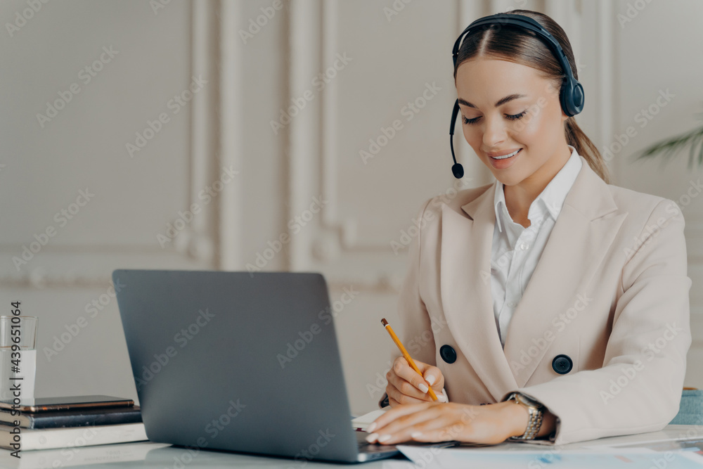 Positive young businesswoman in headset taking part in web conference Positive young businesswoman in headset taking part in web conference