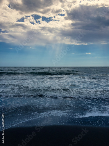 The sea, the blue sky, fluffy clouds and beams of light coming from above
