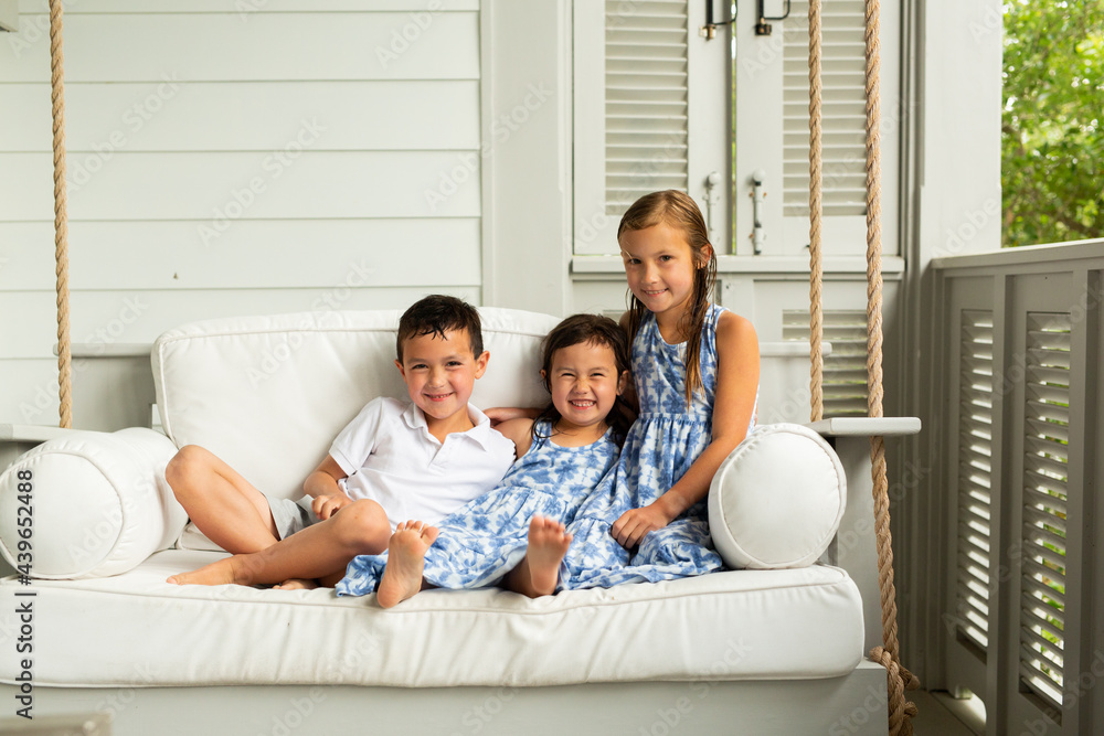 Little Brother and Sisters Sitting on Porch Swing Little Brother and Sisters Sitting on Porch Swing