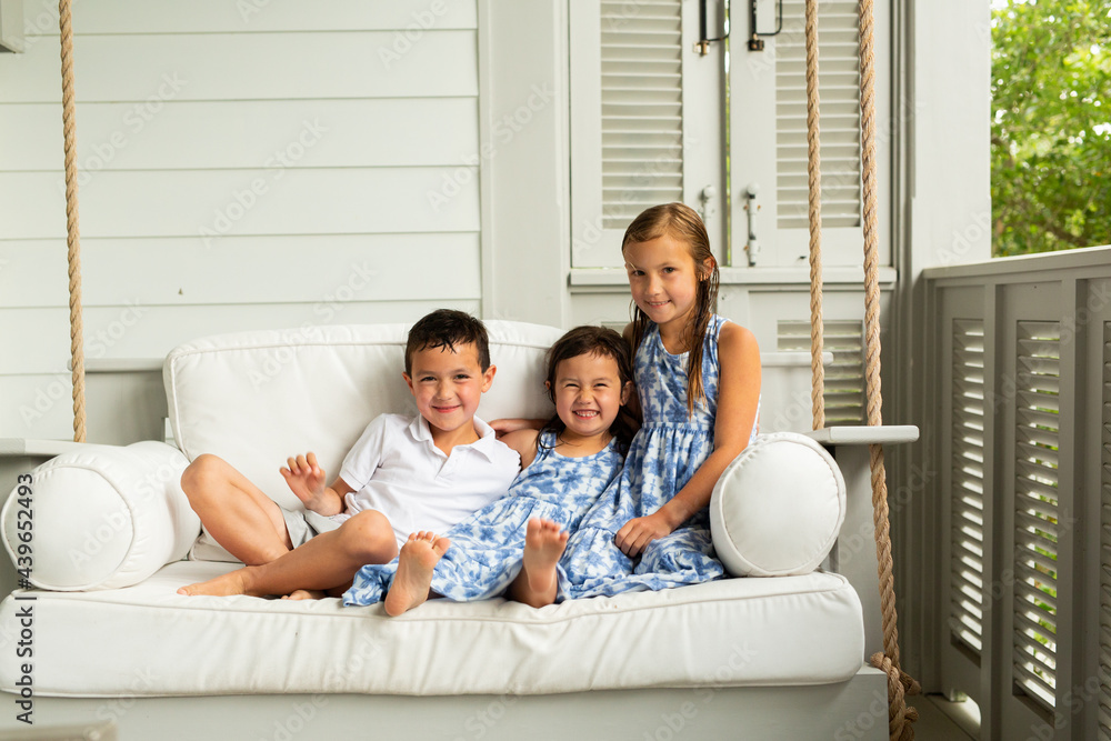 Little Brother and Sisters Sitting on Porch Swing Little Brother and Sisters Sitting on Porch Swing