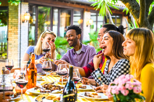 Group of happy multiracial friends having dinner in the restaurant garden - Friendship concept with happy people having fun together toasting drinks and eat at terrace.