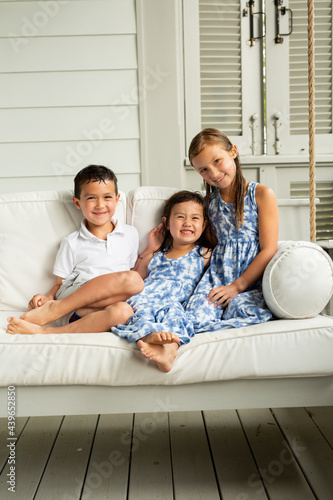 Little Brother and Sisters Sitting on Porch Swing
