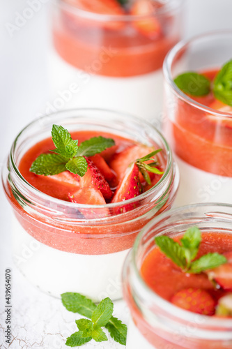 Panna cotta in glass jars with strawberry sauce.