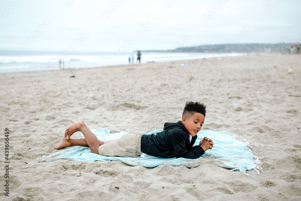 Black boy lying on stomach on beach Black boy lying on stomach on beach