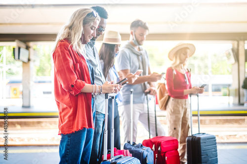 Multiracial group of friends with face mask using smartphone - Young people checking online reservations at train station - New normal travel and lifestyle concept - Focus on the girl in front