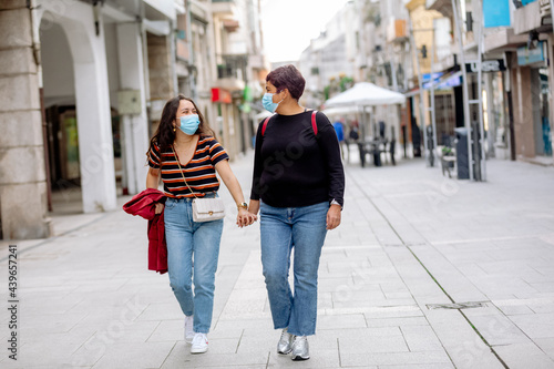 Mother and daughter wearing masks walking around an old town in Spain photo