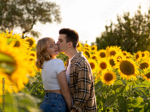 Tableau sur toile Pareja joven disfrutando de sus vacaciones en un campo de girasoles durante la p