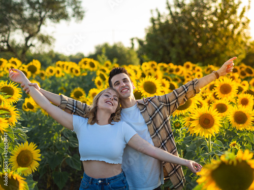 Pareja joven disfrutando de sus vacaciones de verano en un campo de girasoles photo