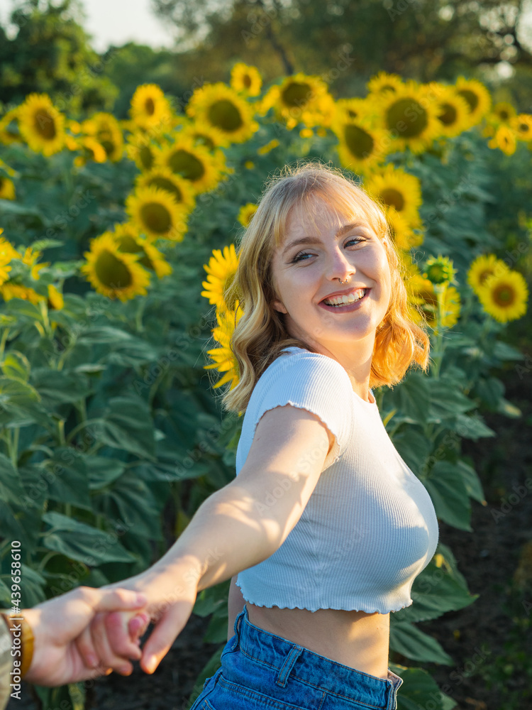 Pareja alegre celebrando sus vacaciones de verano en un campo de girasoles Pareja alegre celebrando sus vacaciones de verano en un campo de girasoles