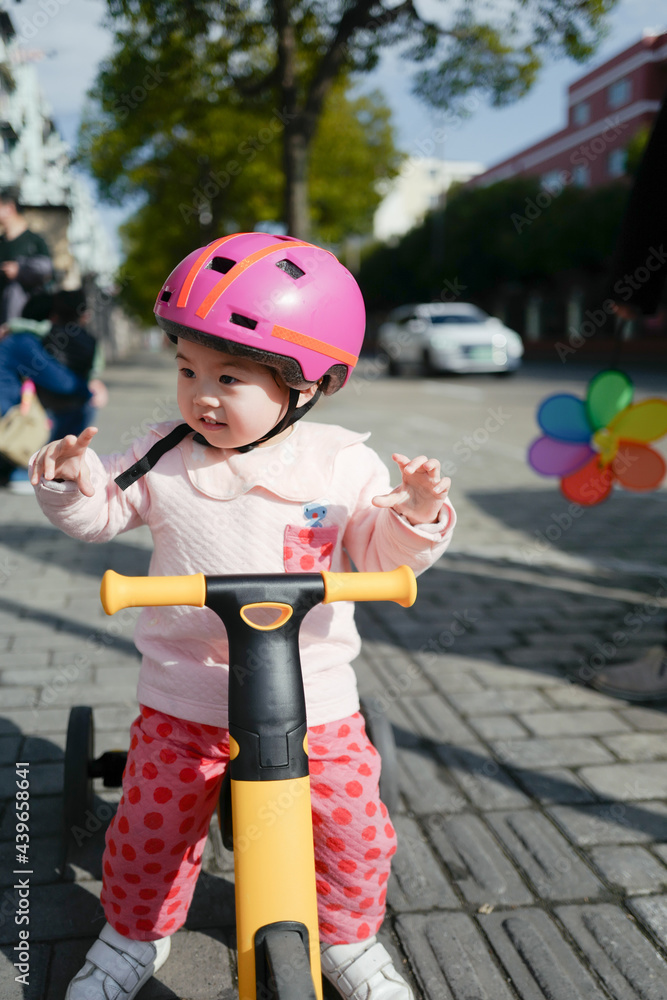 Baby wearing a helmet riding a tricycle StockFoto Adobe Stock