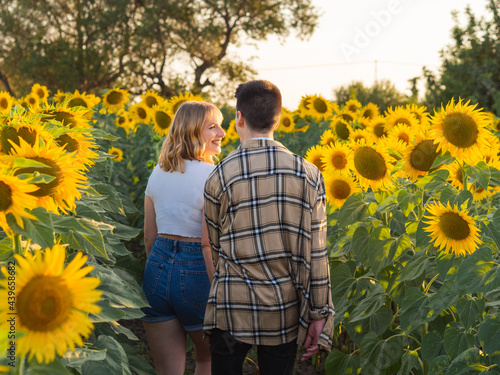 Pareja alegre celebrando sus vacaciones de verano en un campo de girasoles 