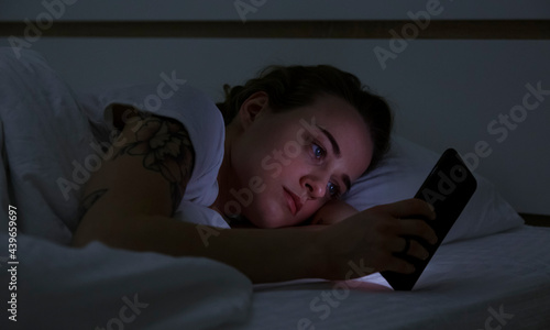 Young woman using smartphone in bed
