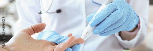 Tableau sur toile Doctor with gloves piercing patients finger with lancet closeup