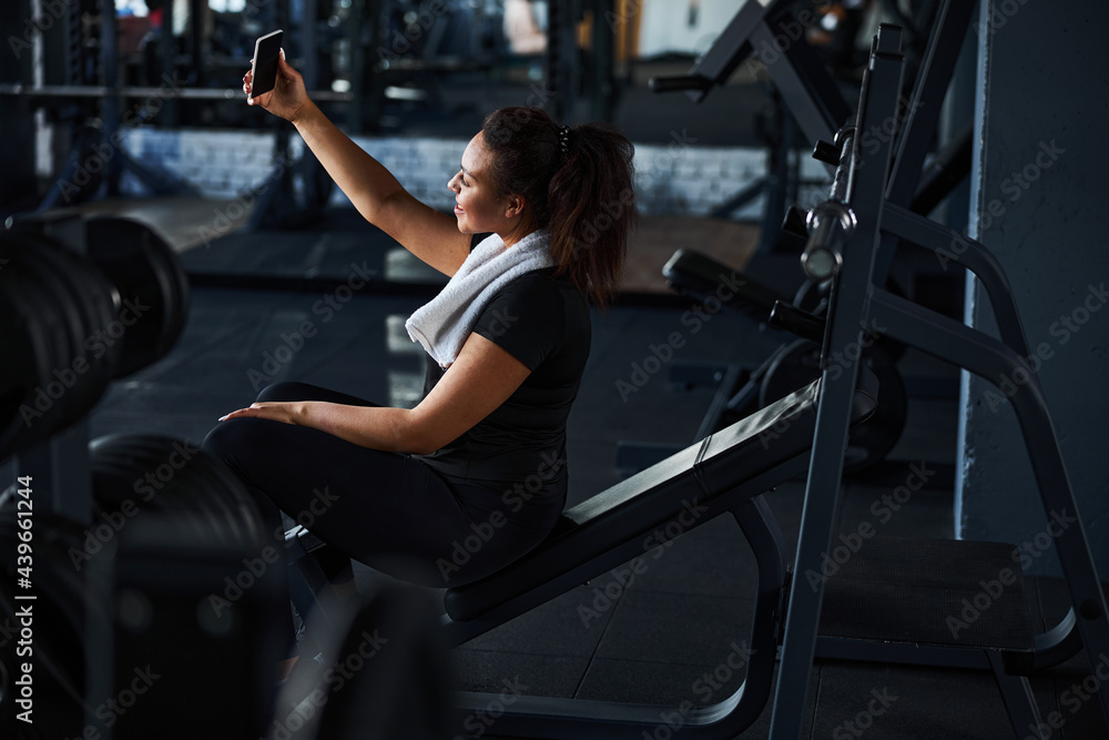 Jolly young woman taking photo in gym Jolly young woman taking photo in gym