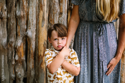 Grumpy Little Boy Holding Mom's Arm