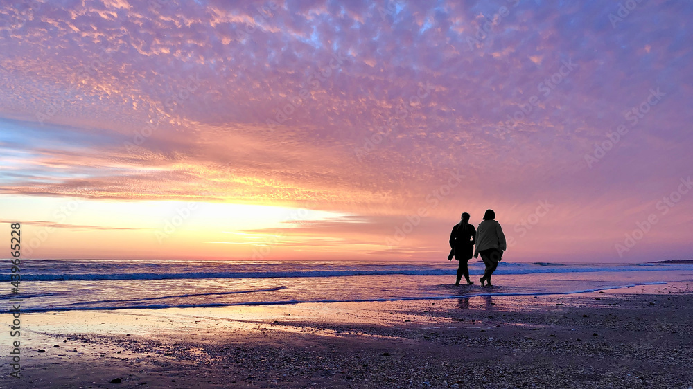 Zwei Frauen spazieren während des Sonnenuntergangs den Strand entlang