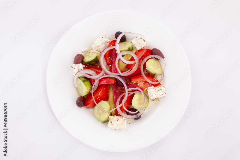 Top down view of salad with cheese and fresh vegetables in white plate. Greek salad. Top down view of salad with cheese and fresh vegetables in white plate. Greek salad.